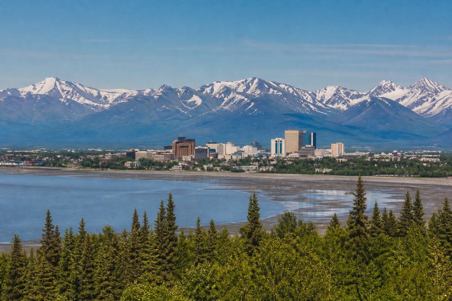 Illustration photographique : la ville d’Anchorage, les conifères et les montagnes d’Alaska.