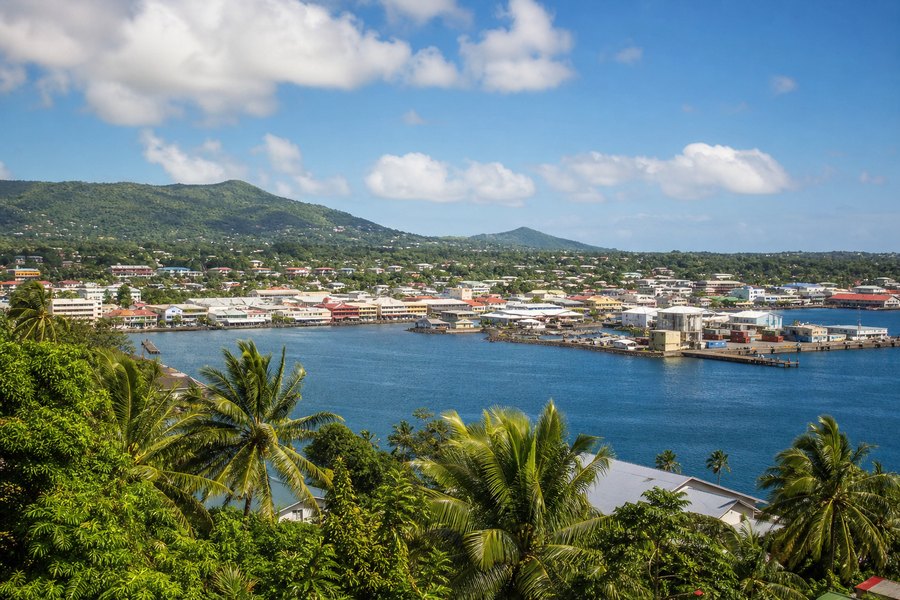 Illustration photographique : le port tropical, les palmiers et les collines verdoyantes d’Apia. Illustration éditoriale, scène imaginaire.