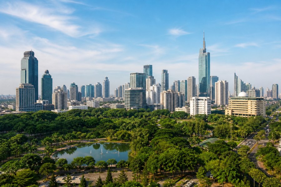 Illustration photographique : les jardins tropicaux et la silhouette contemporaine de Jakarta. Illustration éditoriale, scène imaginaire.