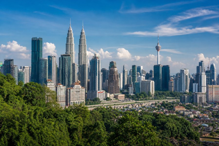 Illustration photographique : la végétation tropicale et les tours de Kuala Lumpur. Illustration éditoriale, scène imaginaire.