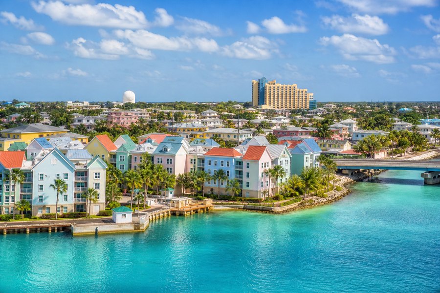 Illustration photographique : le port turquoise, les palmiers et les façades colorées de Nassau. Illustration éditoriale, scène imaginaire.